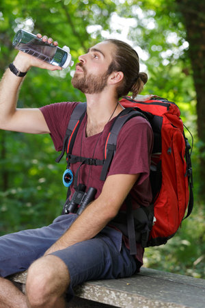 young male hiker drinking water