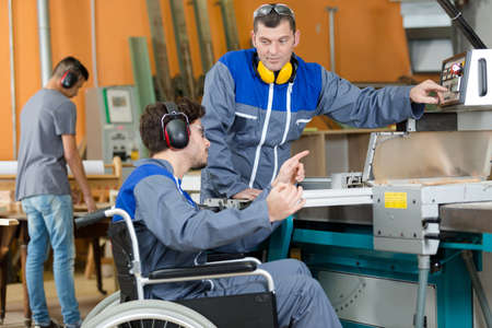 disabled worker in wheelchair in factory on the machineの写真素材
