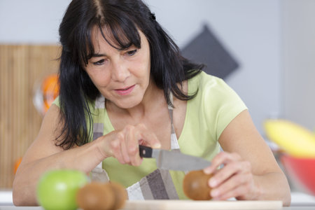 senior female arms chopping tomatoes in kitchenの写真素材