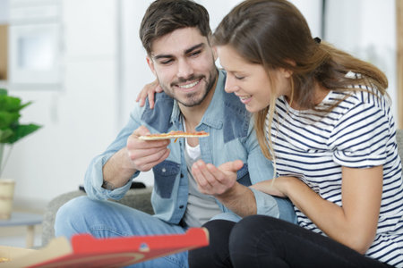 couple sharing pizza and eating together happilyの写真素材