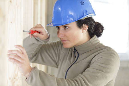 young smiling woman assembling wooden wallの写真素材