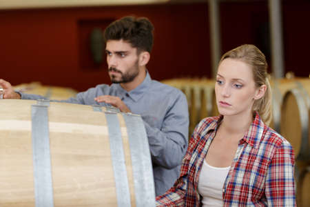 two staff inspecting barrels in a wine factory warehouseの写真素材