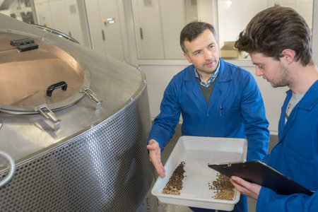 man by industrial machine showing tray of coffee grains