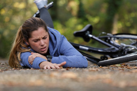woman cyclist with injuries after falling down from bicycle
