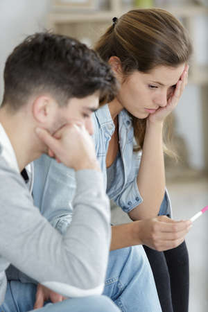 upset couple looking at pregnancy testの写真素材