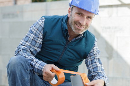 worker insulating heating system pipes with foil