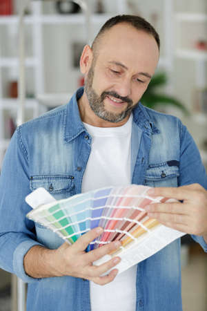 man at home looking through paint colour chartsの写真素材