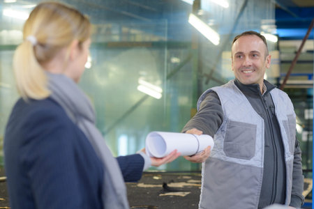 happy industrial engineer giving blueprint to worker