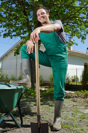 portrait of professional gardener leg raised on wheelbarrow