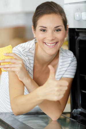 woman cleaning her oven giving thumbs up gestureの写真素材