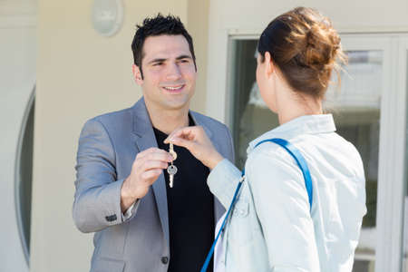 keys being passed between man and woman outside propertyの写真素材