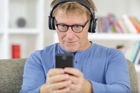 cheerful mature man listening to music from smartphoneの写真素材