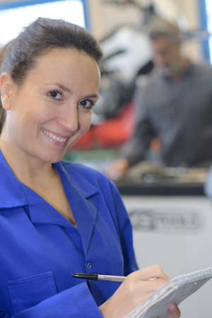 portrait of female worker with notebook shop counter in backgroundの写真素材