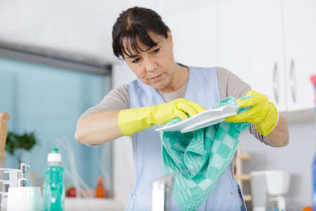 adult woman washes dishes at home in the kitchenの写真素材
