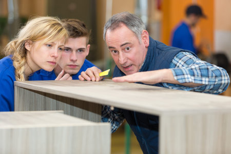 industrial woodworker giving information to apprentice