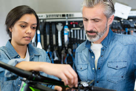 woman and man as bike mechanics in workshop reparingの写真素材