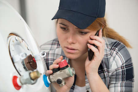 Woman in shirt near boiler control panelの写真素材