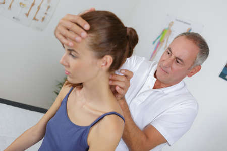 Physiotherapist massaging the neck of young patientの写真素材