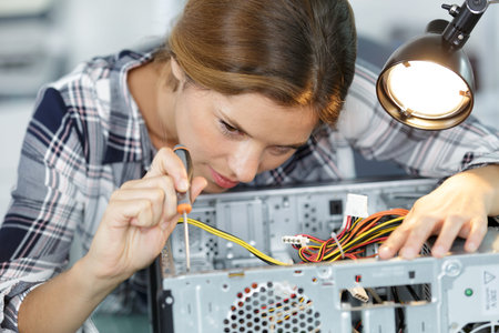 young woman fixing a desktop computer seated at a table