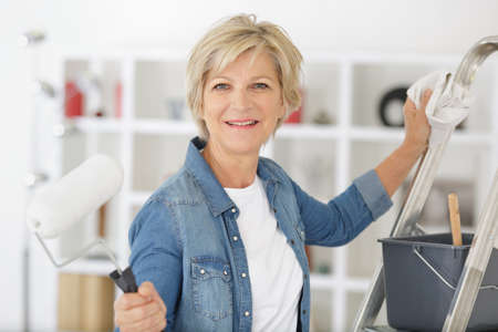 portrait of mature woman holding paint rollerの写真素材