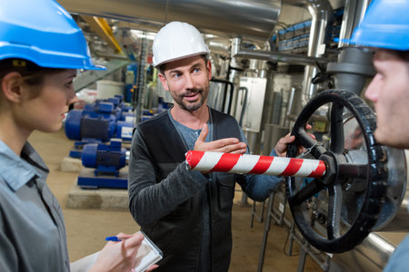 electrical engineer with apprentices working at control room