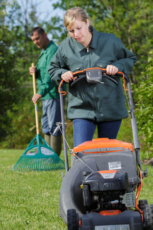 professional gardening team using rake and mower