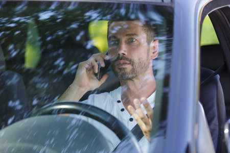 man driver talking on a mobile phone in the car
