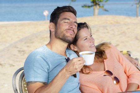 couple relaxing with a coffee in cafe by the beachの写真素材
