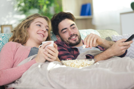 young couple watching tv and eating pop-corn