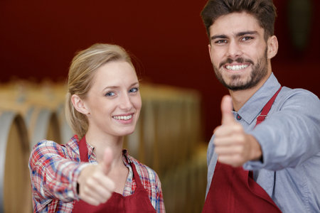young couple of wine-workers showing thumbs up