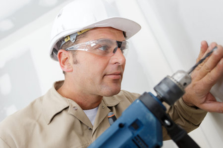 carpenter drills a hole with an electrical drill
