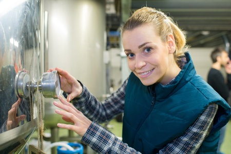 female maintenance worker examining brewery machine at brewery