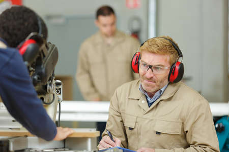 workers wearing earmuffs in workshopの写真素材