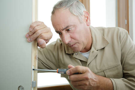 man screwing and repairing door handleの写真素材