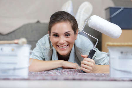 portrait of woman layed on floor holding a paint rollerの写真素材