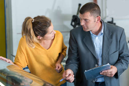 suited man in garage discussing car repairs with attractive womanの写真素材