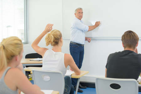 teacher writing on whiteboar giving a classの写真素材