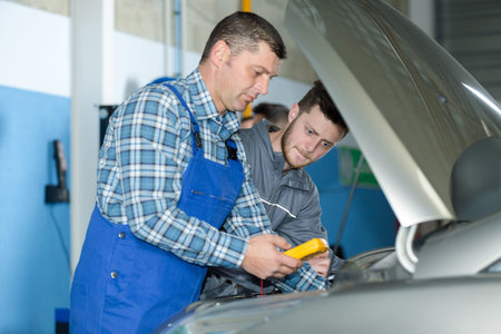 auto mechanic using digital multimeter to check car battery