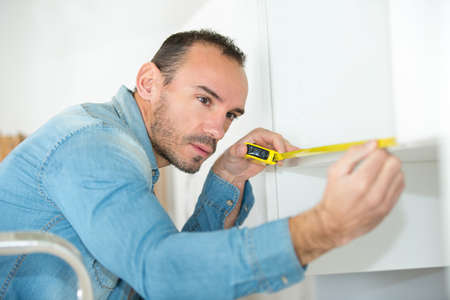 a man measuring kitchen cupboardの写真素材