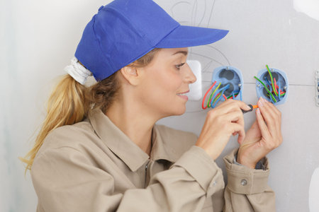 happy female electrician fixing socket electricity