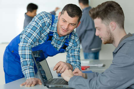 teacher helping student using laptopの写真素材