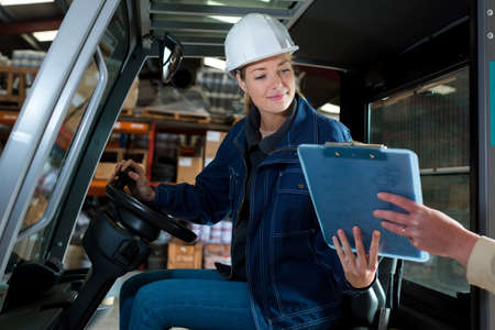 female forklift driver being passed a clipboardの写真素材