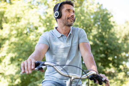 mature man on bicycle wearing headphonesの写真素材
