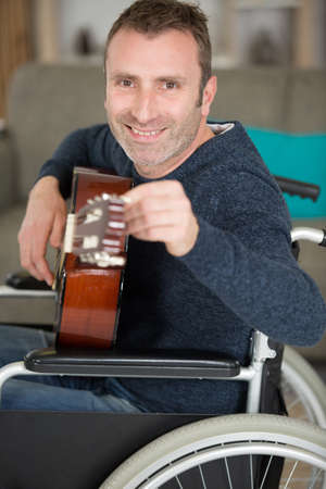 a man on the wheelchair playing the guitarの写真素材