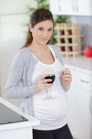pregnant woman with cigarette and glass of wineの写真素材
