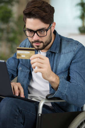 disabled man using credit card to shop the internetの写真素材