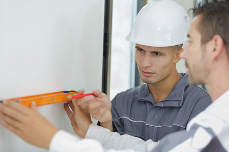builder and apprentice inspecting the level