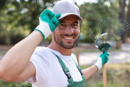 male gardener with rake touching his cap in greeting