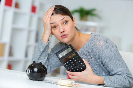 unhappy woman with calculator and piggy bank
