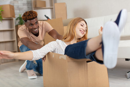 man pushing laughing wife in carton box